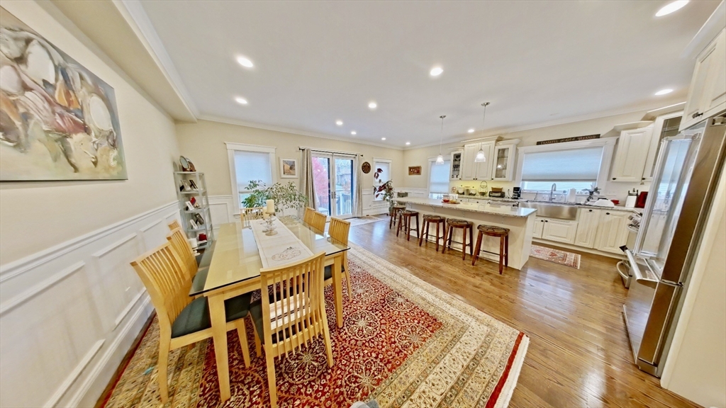 a living room with stainless steel appliances furniture wooden floor and a rug