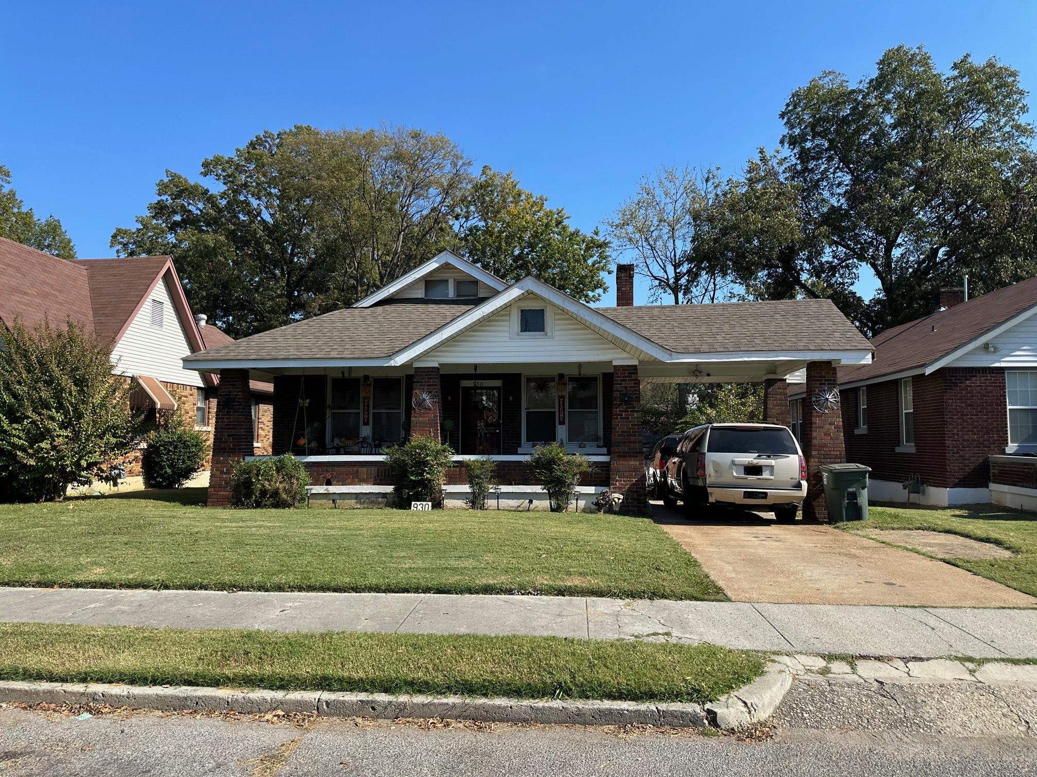 View of front of property with a front yard, a porch, and a carport