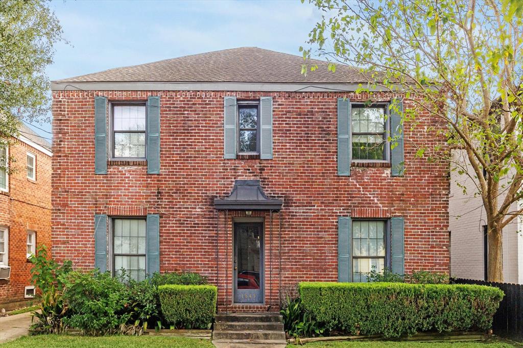 front view of a brick house with a yard