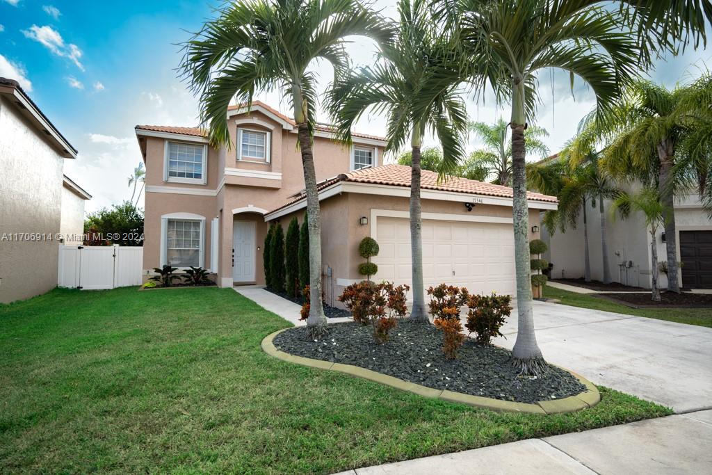 a view of a white house with a yard plants and palm trees