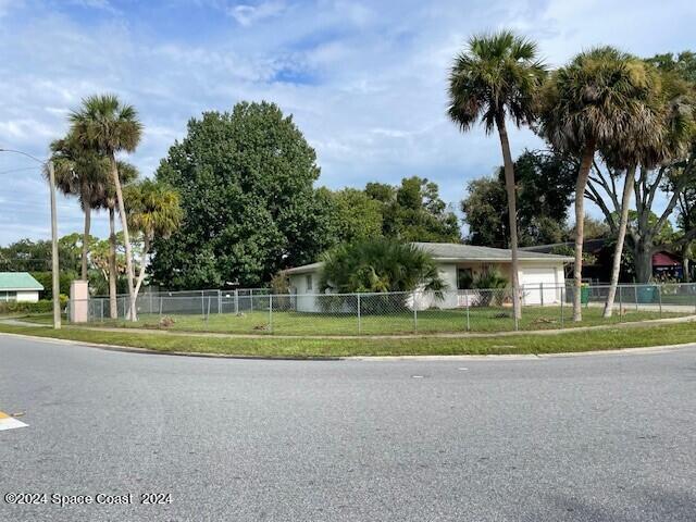 a view of big house with a big yard and palm trees