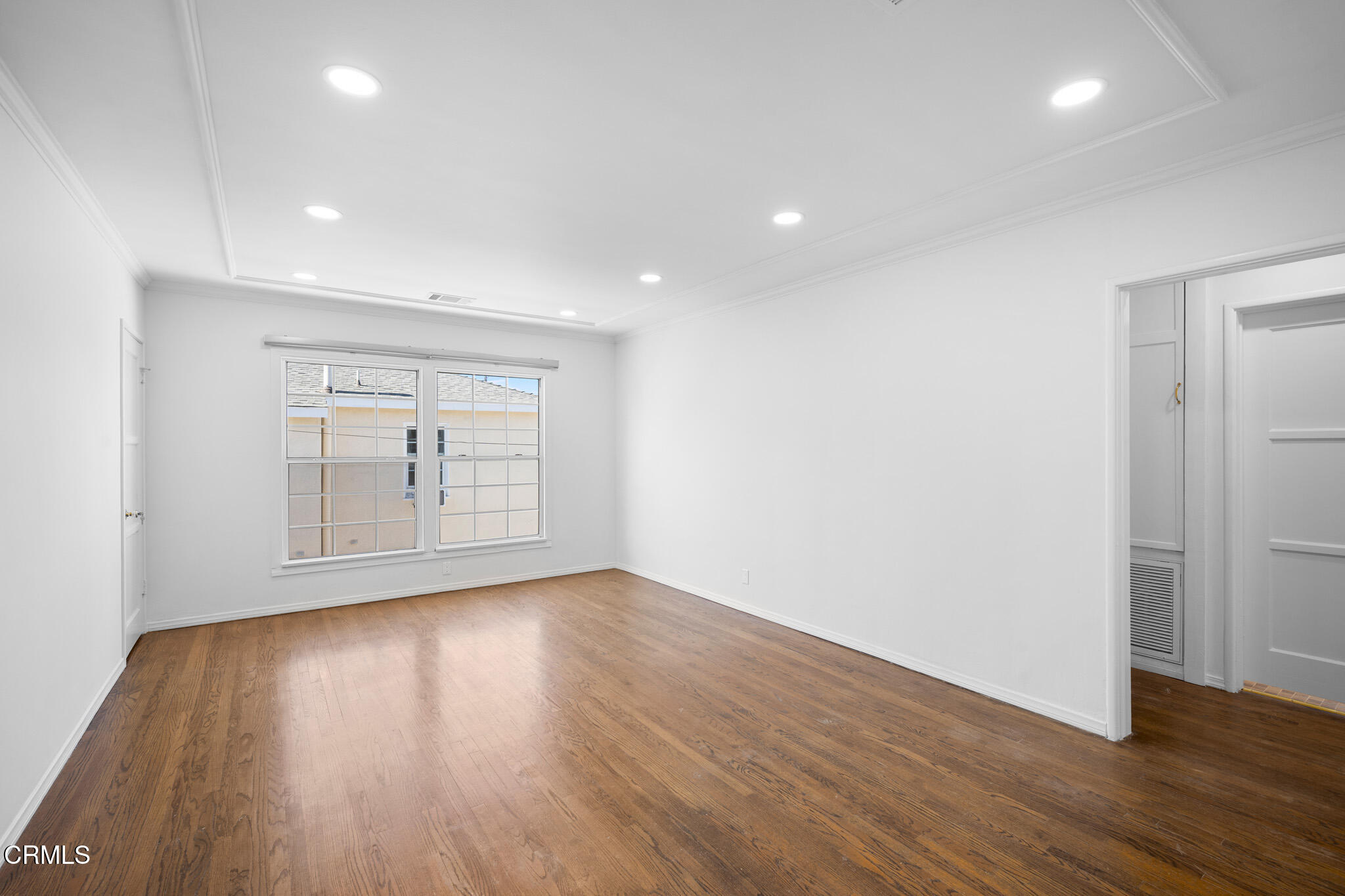 a view of an empty room with wooden floor and a window