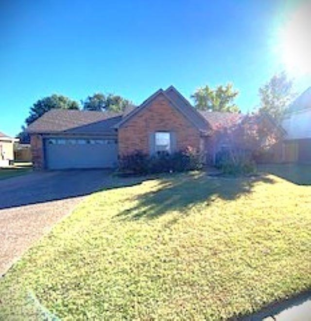 View of front of property with a garage and a front lawn