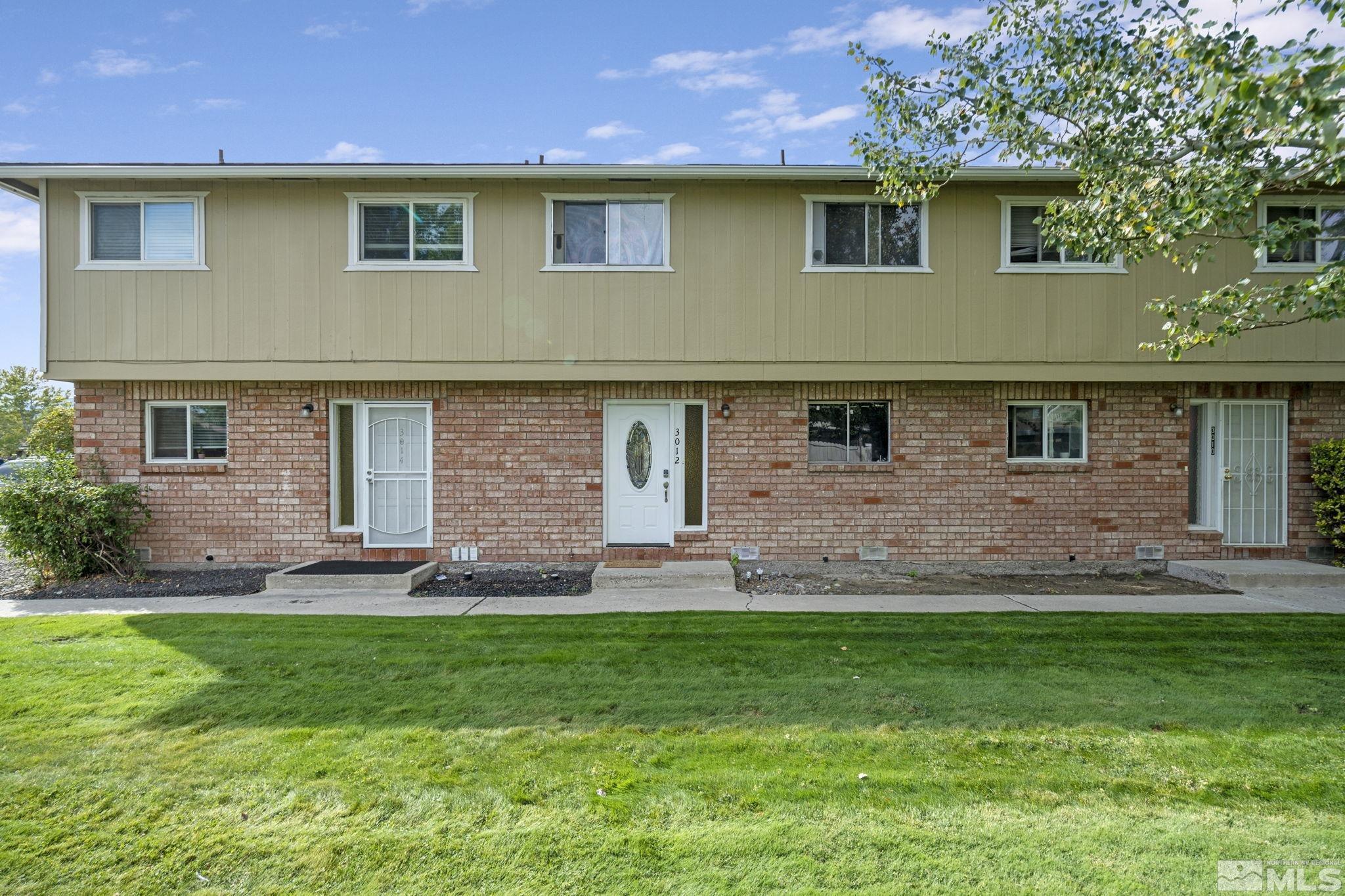 a front view of brick house with a yard