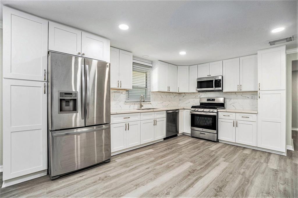 a kitchen with white cabinets stainless steel appliances and a refrigerator