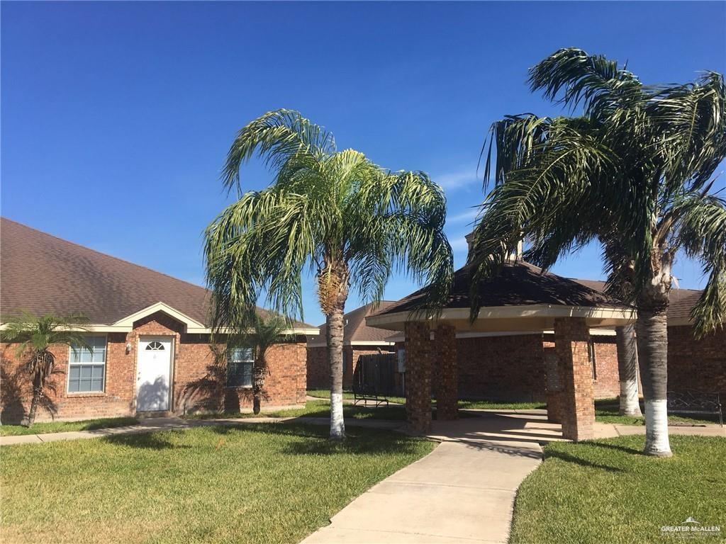 a view of a house with a yard and palm trees