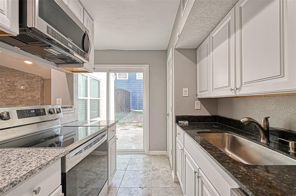 a kitchen with granite countertop a sink a stove and cabinets