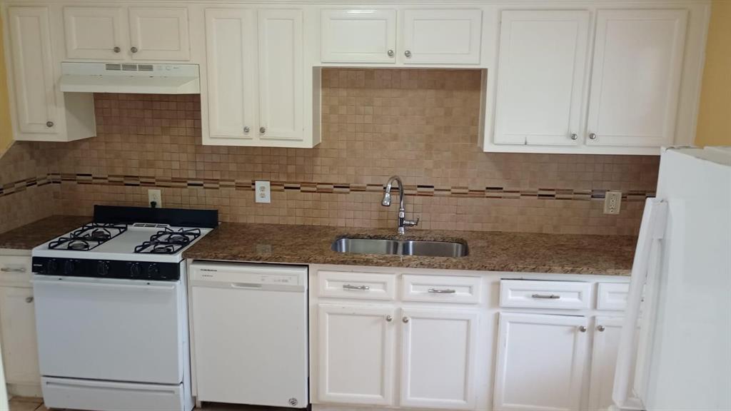 a kitchen with granite countertop white cabinets and white appliances