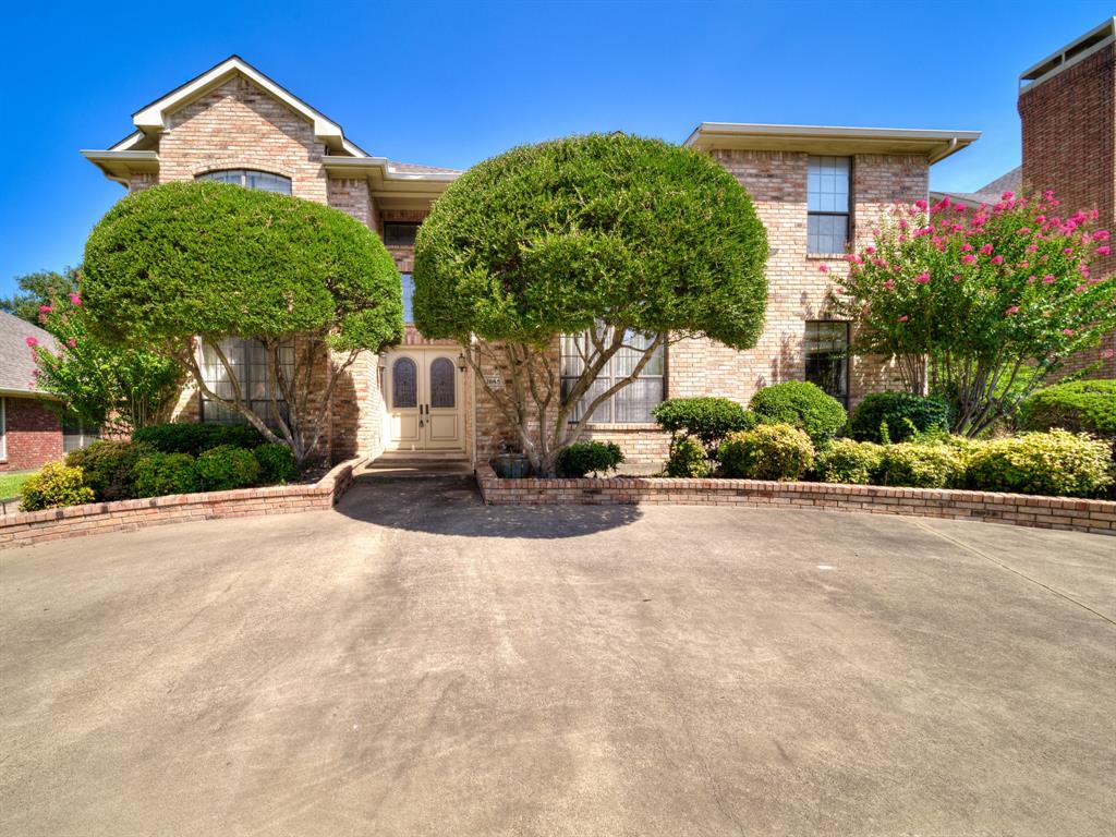 a view of a house with potted plants and a large tree