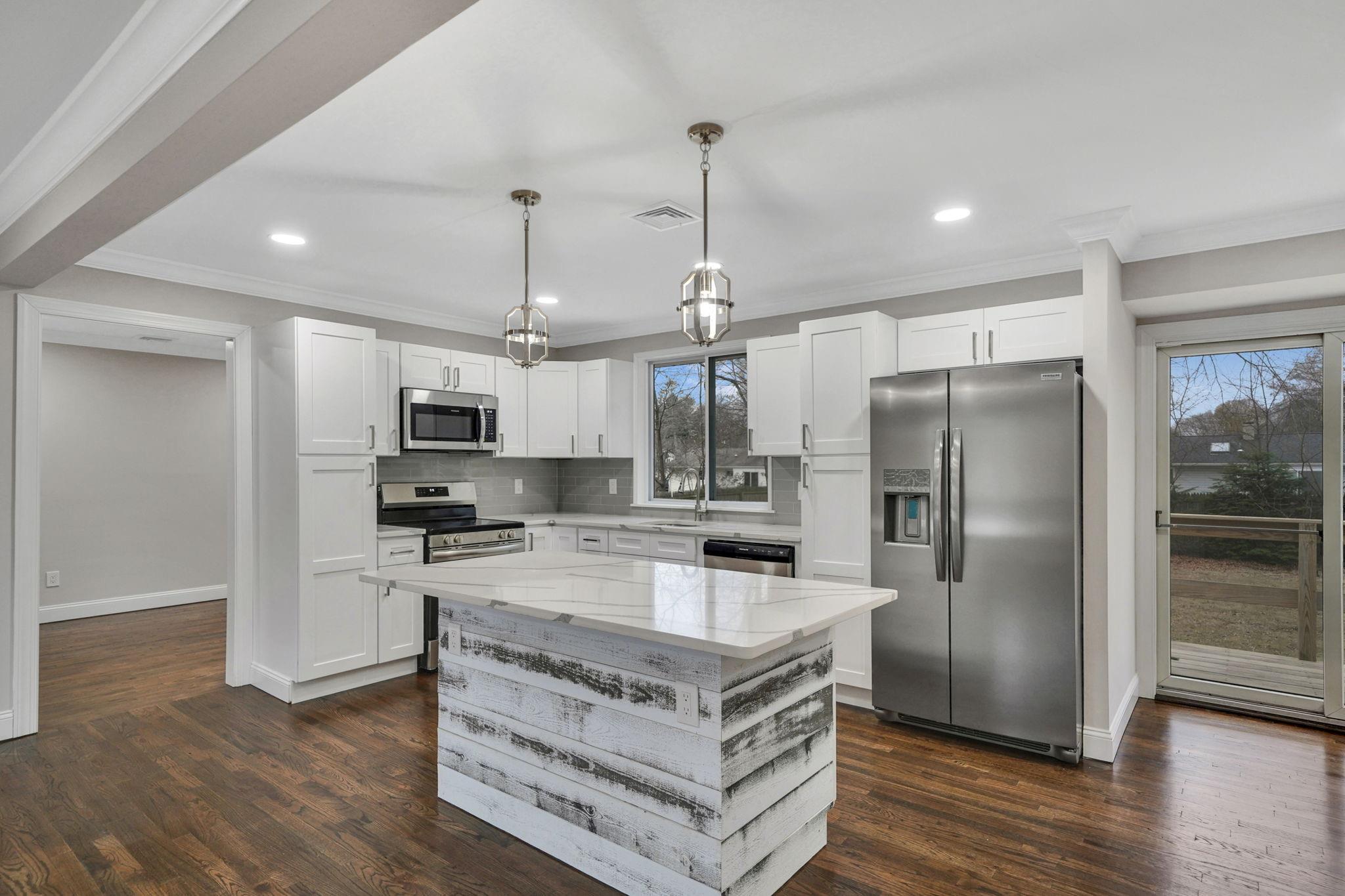 Kitchen with decorative light fixtures, a kitchen island, dark hardwood / wood-style flooring, white cabinetry, and stainless steel appliances