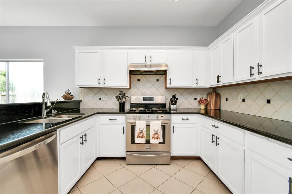 a white kitchen with granite countertop white cabinets and stainless steel appliances