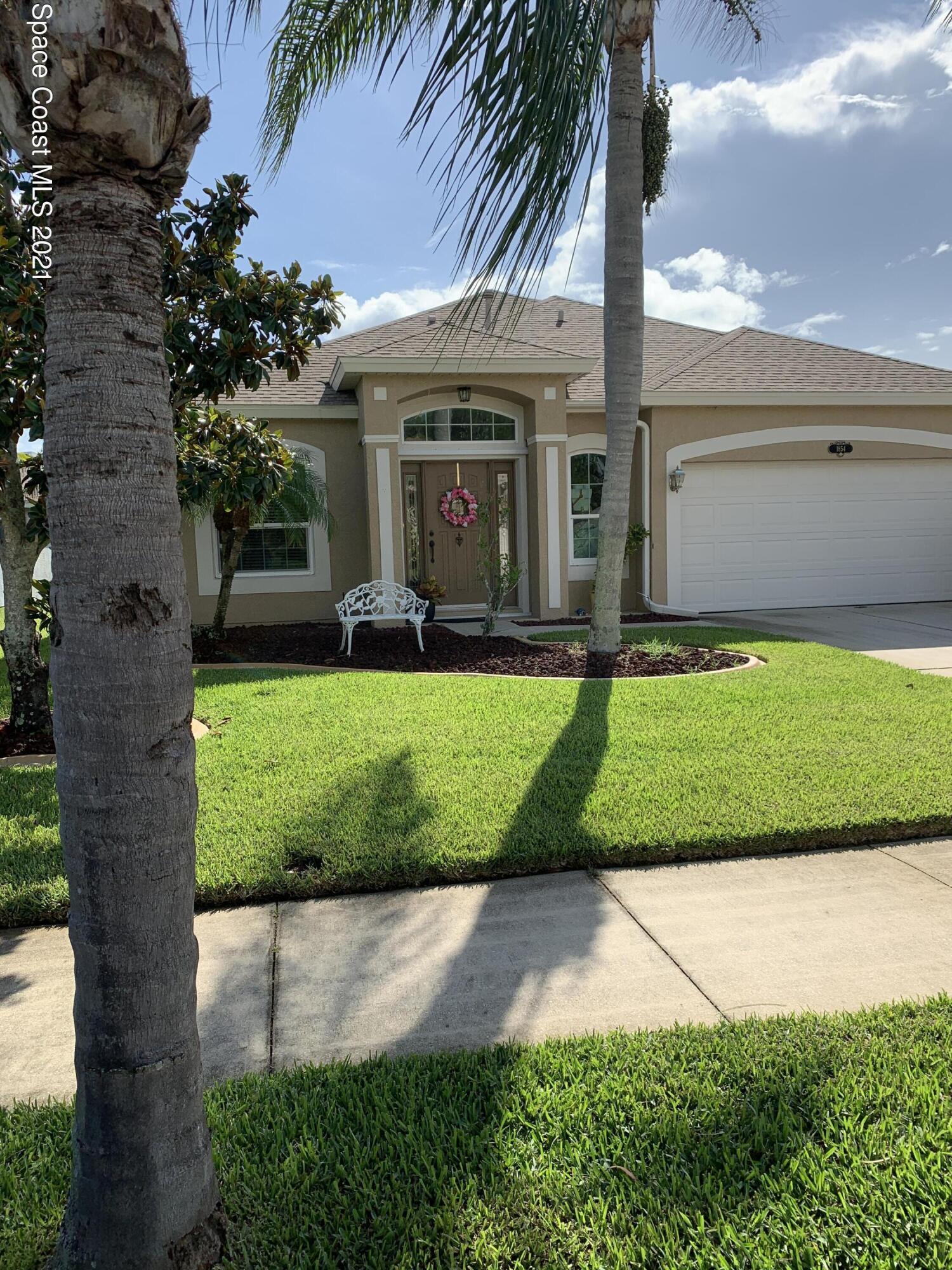 a view of a white house with a big yard and potted plants