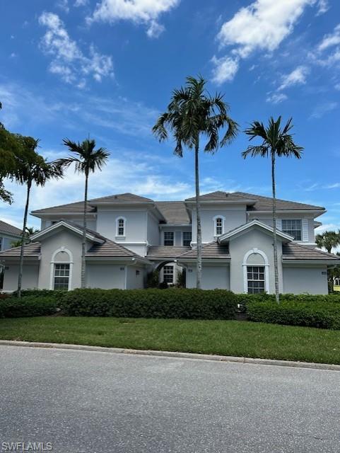 a front view of a house with a garden and trees