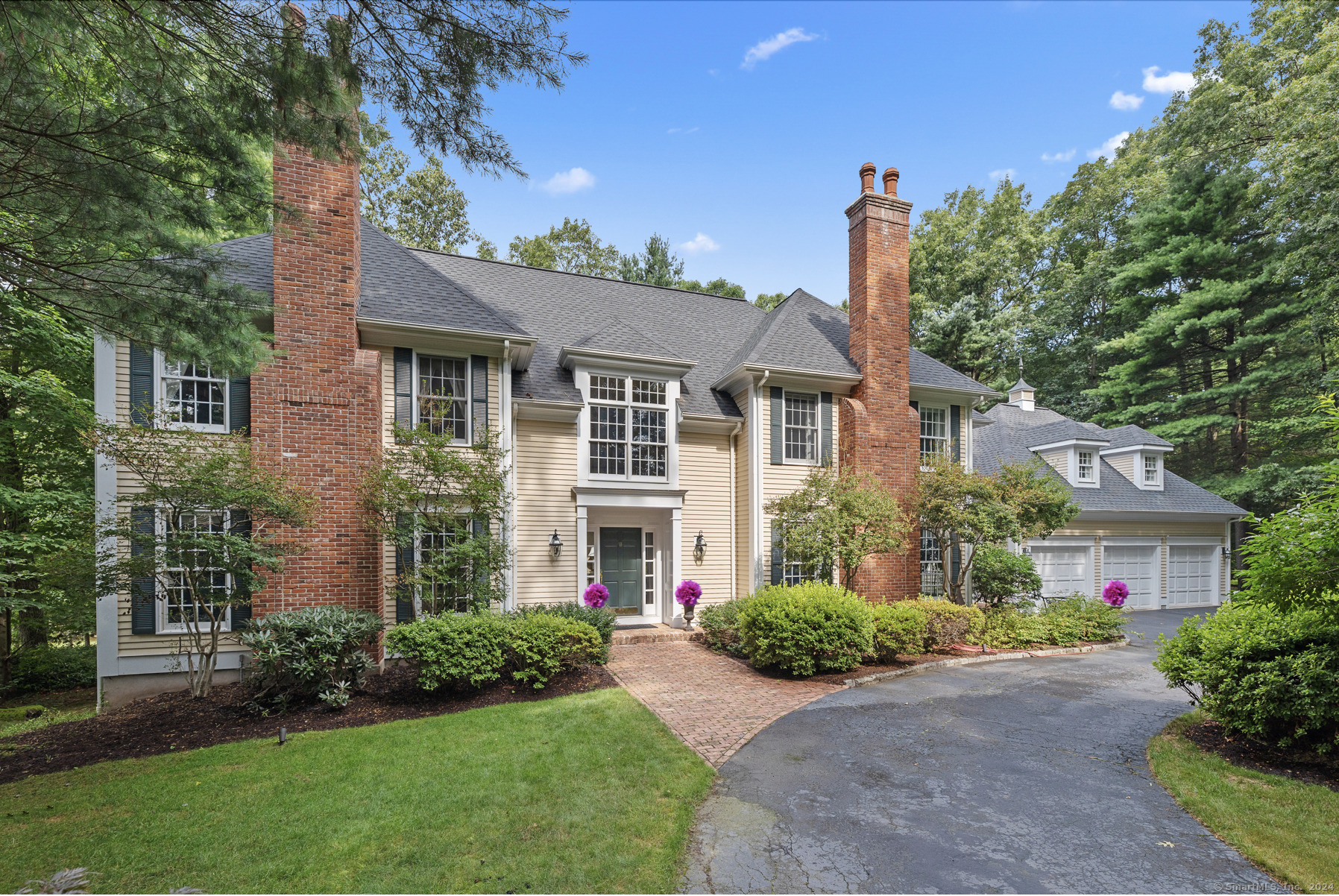 Welcome to 4 Pembroke Hill! The circular drive escorts guests to the covered formal entrance flanked by handsome twin brick chimneys.