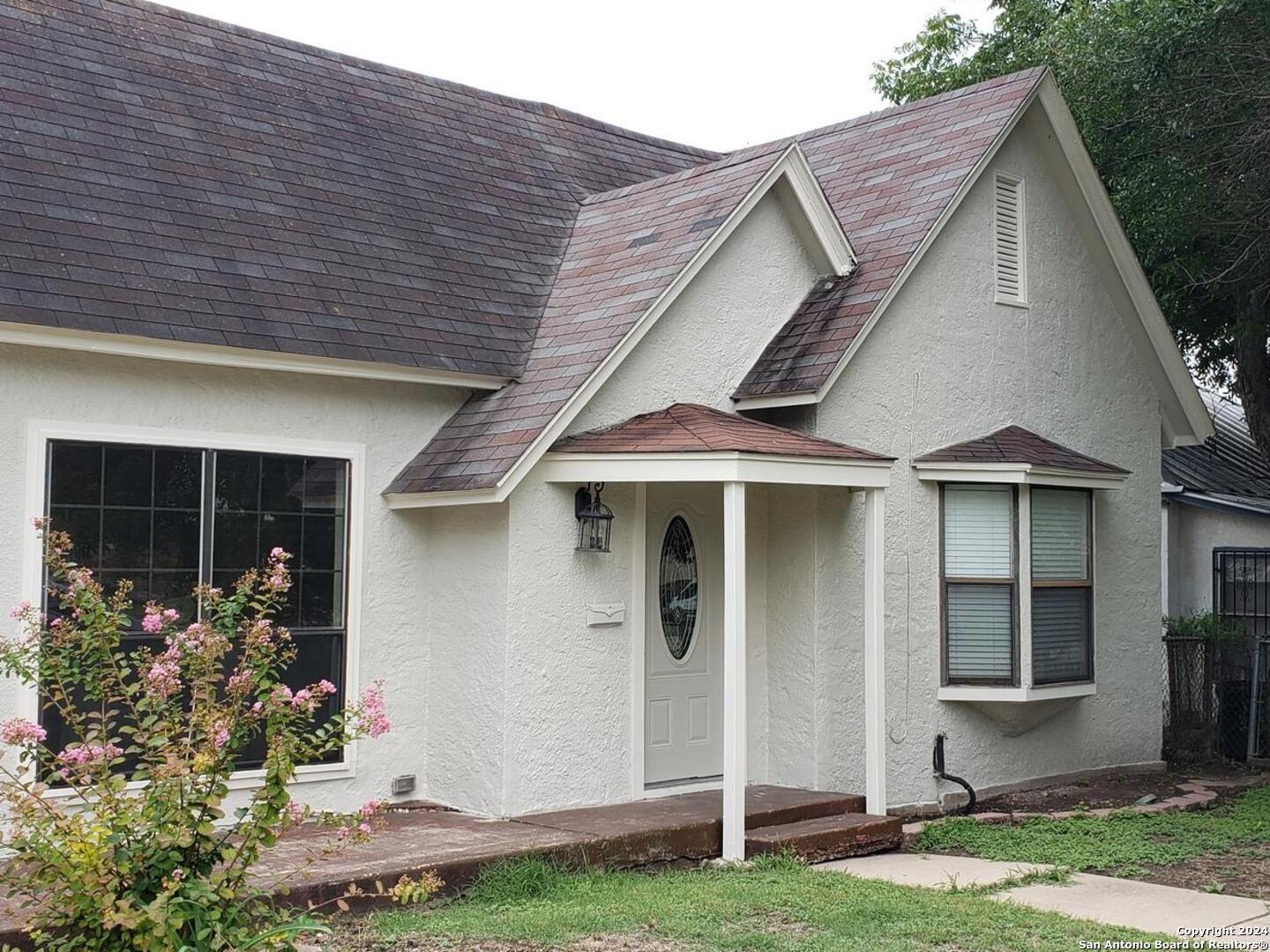 a front view of a house with a yard and potted plants