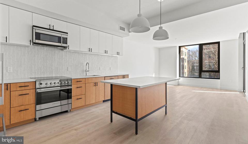 a kitchen with stainless steel appliances a stove a sink and a microwave