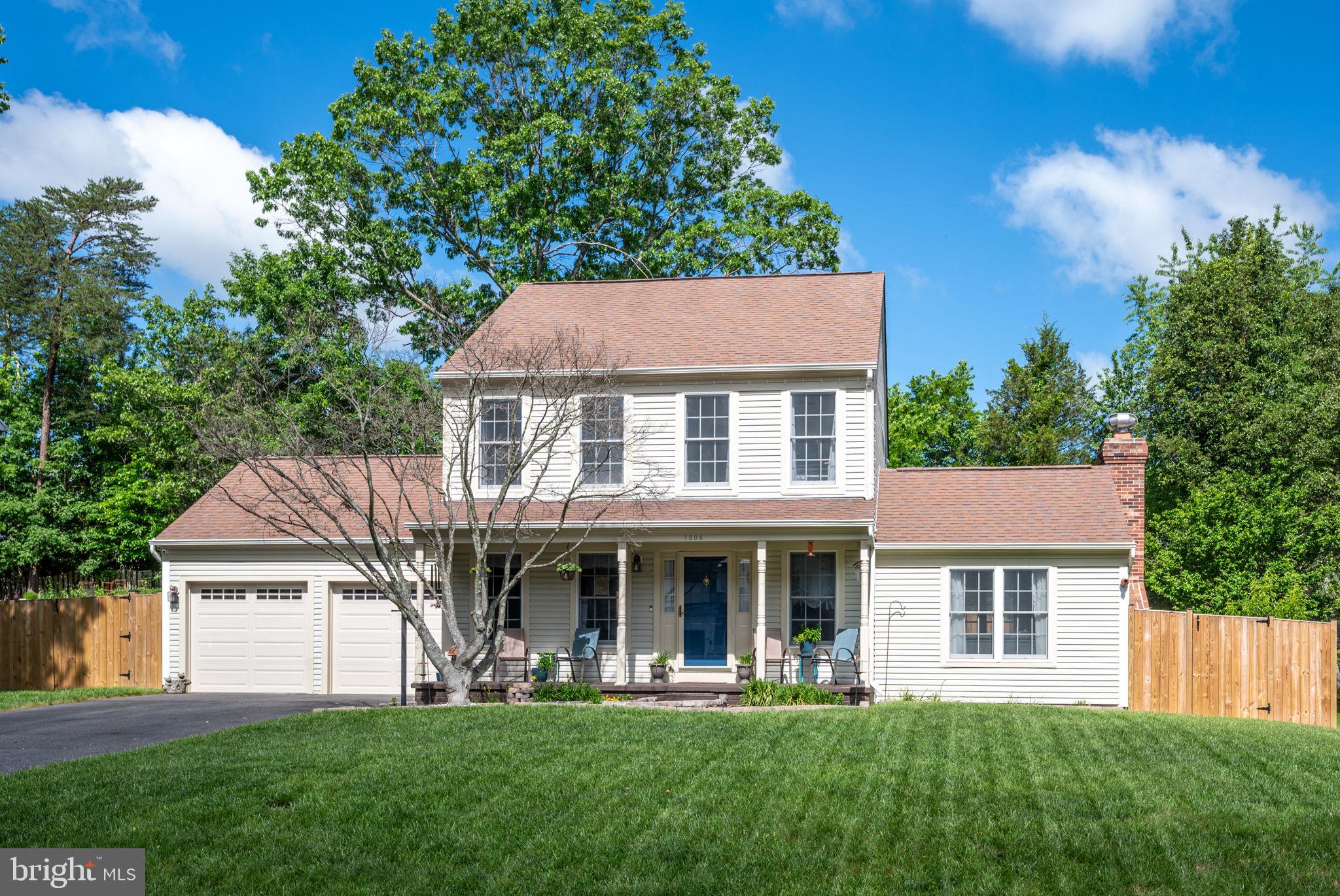 a front view of a house with a garden and trees