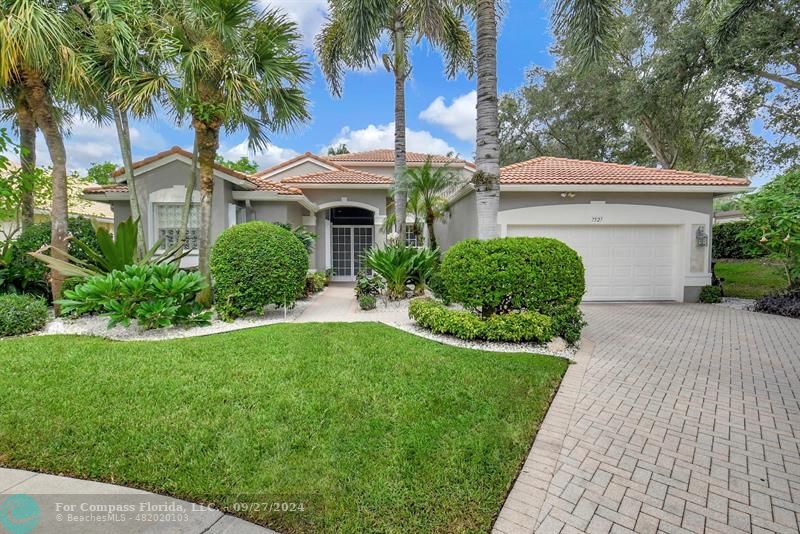 a front view of a house with a garden and palm trees