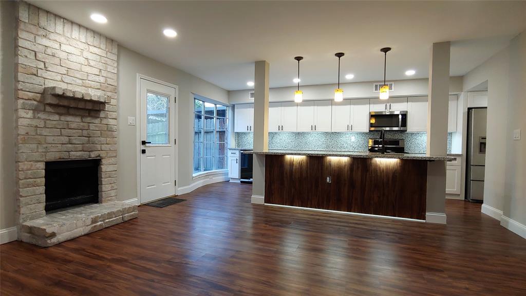 an open kitchen with a refrigerator and wooden floor