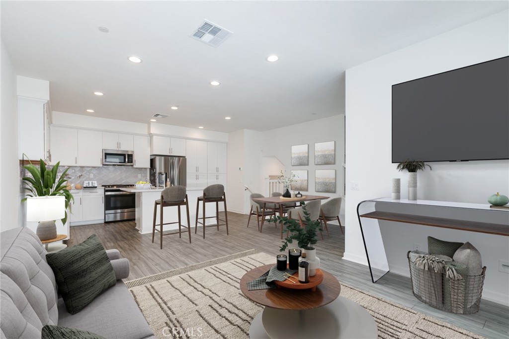 a living room with furniture kitchen view and a flat screen tv