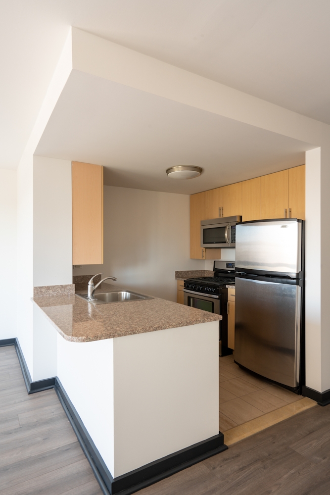 a kitchen with kitchen island granite countertop a sink and a refrigerator