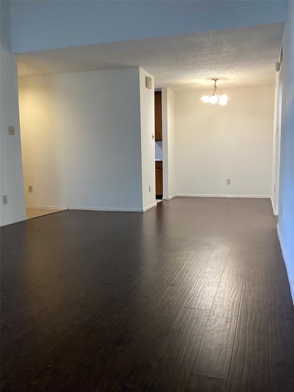 an empty room with wooden floor and windows with curtains