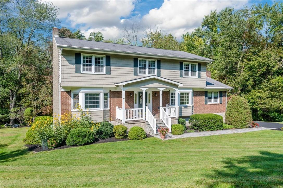 Colonial house featuring a front yard and covered porch