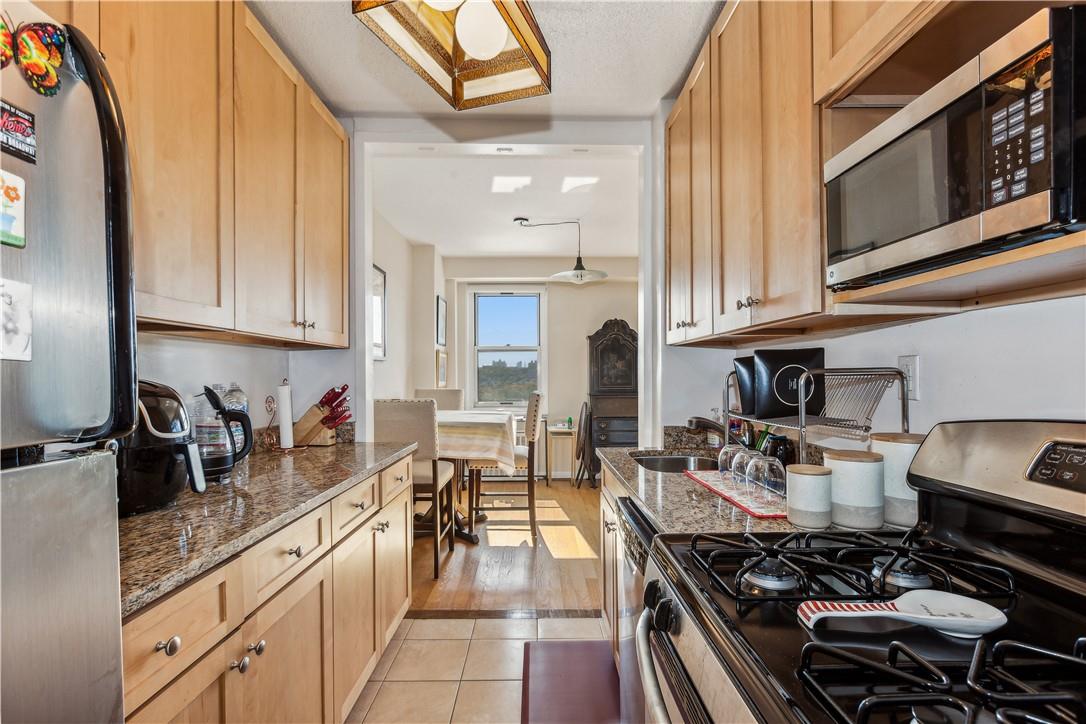 Kitchen featuring dark stone countertops, sink, light brown cabinetry, appliances with stainless steel finishes, and light hardwood / wood-style floors