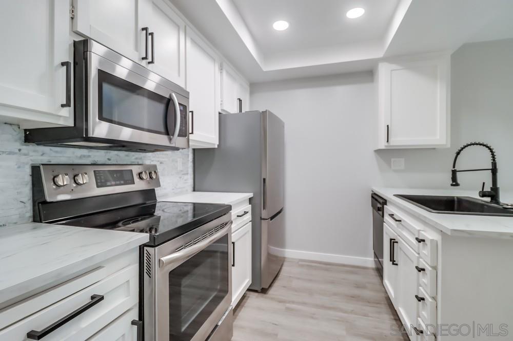 a kitchen with stainless steel appliances a stove microwave and sink