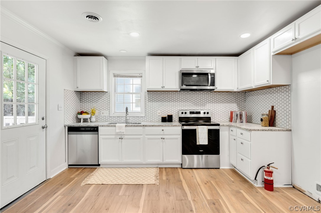 a kitchen with stainless steel appliances granite countertop a stove top oven a sink dishwasher and white cabinets