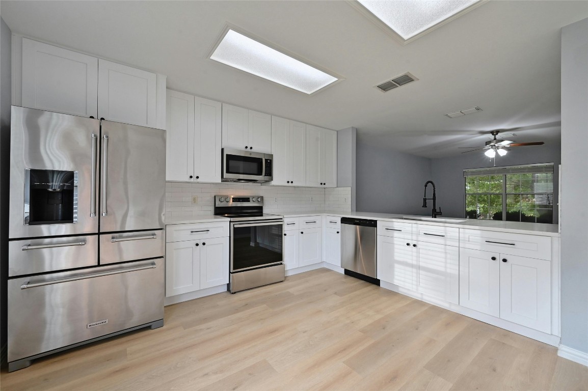 a kitchen with granite countertop white cabinets and stainless steel appliances