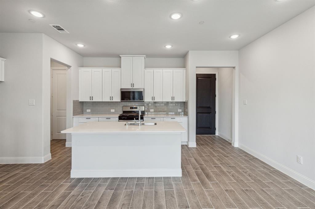 a view of kitchen with stainless steel appliances granite countertop a stove top oven and a refrigerator with wooden floor