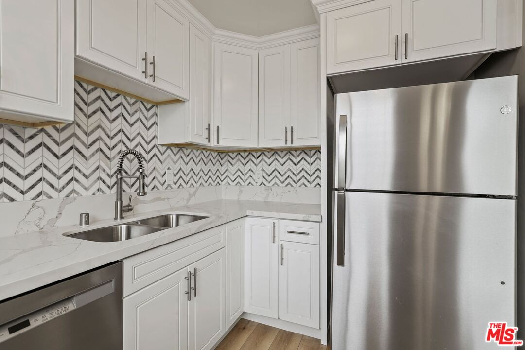 a kitchen with stainless steel appliances a refrigerator a sink and cabinets