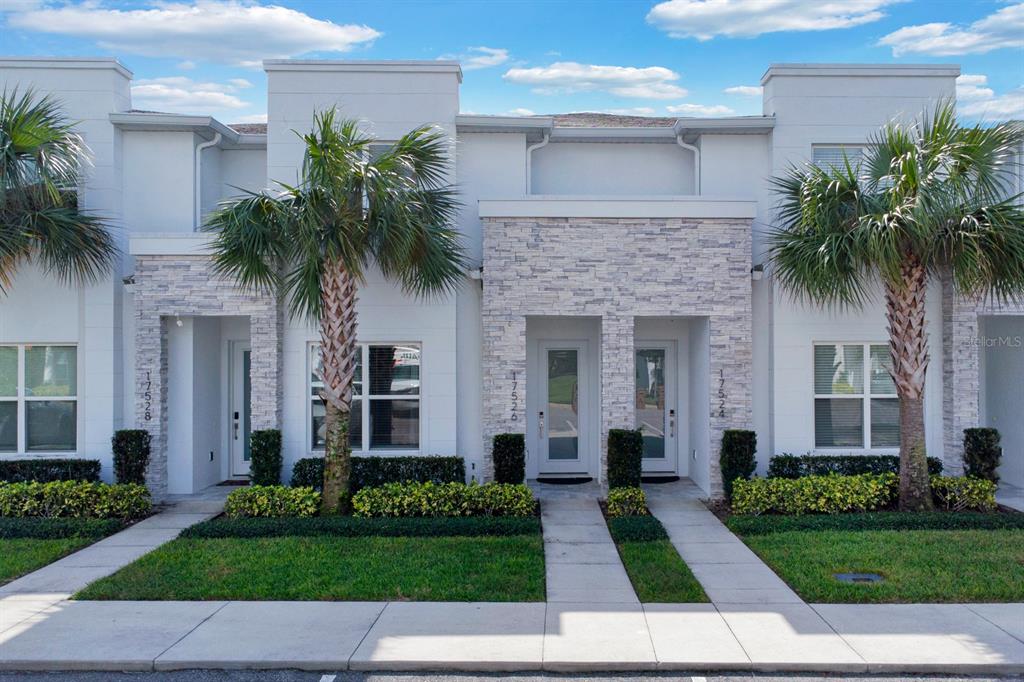 a front view of a house with a garden and palm trees