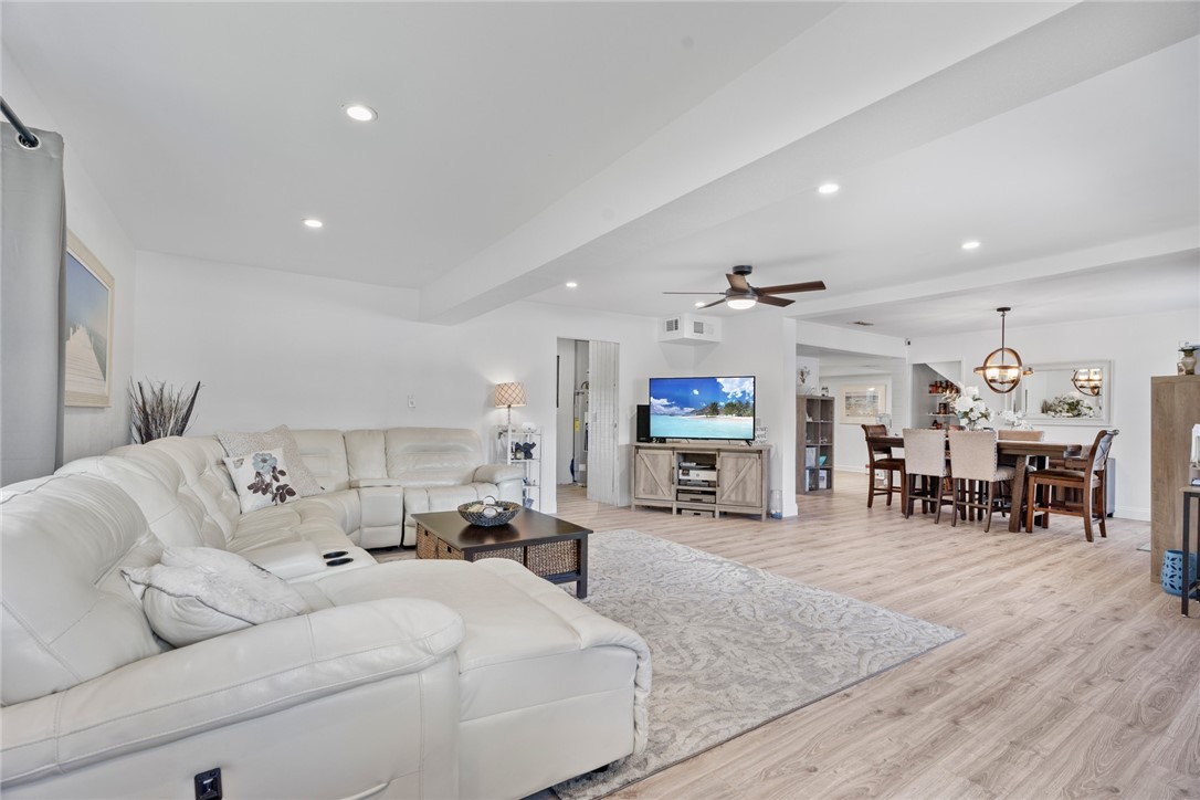 a living room with furniture and a dining table with wooden floor