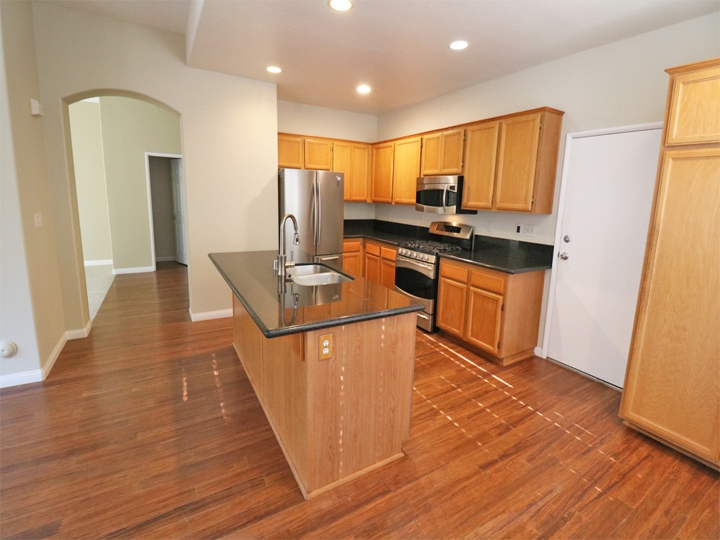 a kitchen with stainless steel appliances granite countertop a sink stove and refrigerator