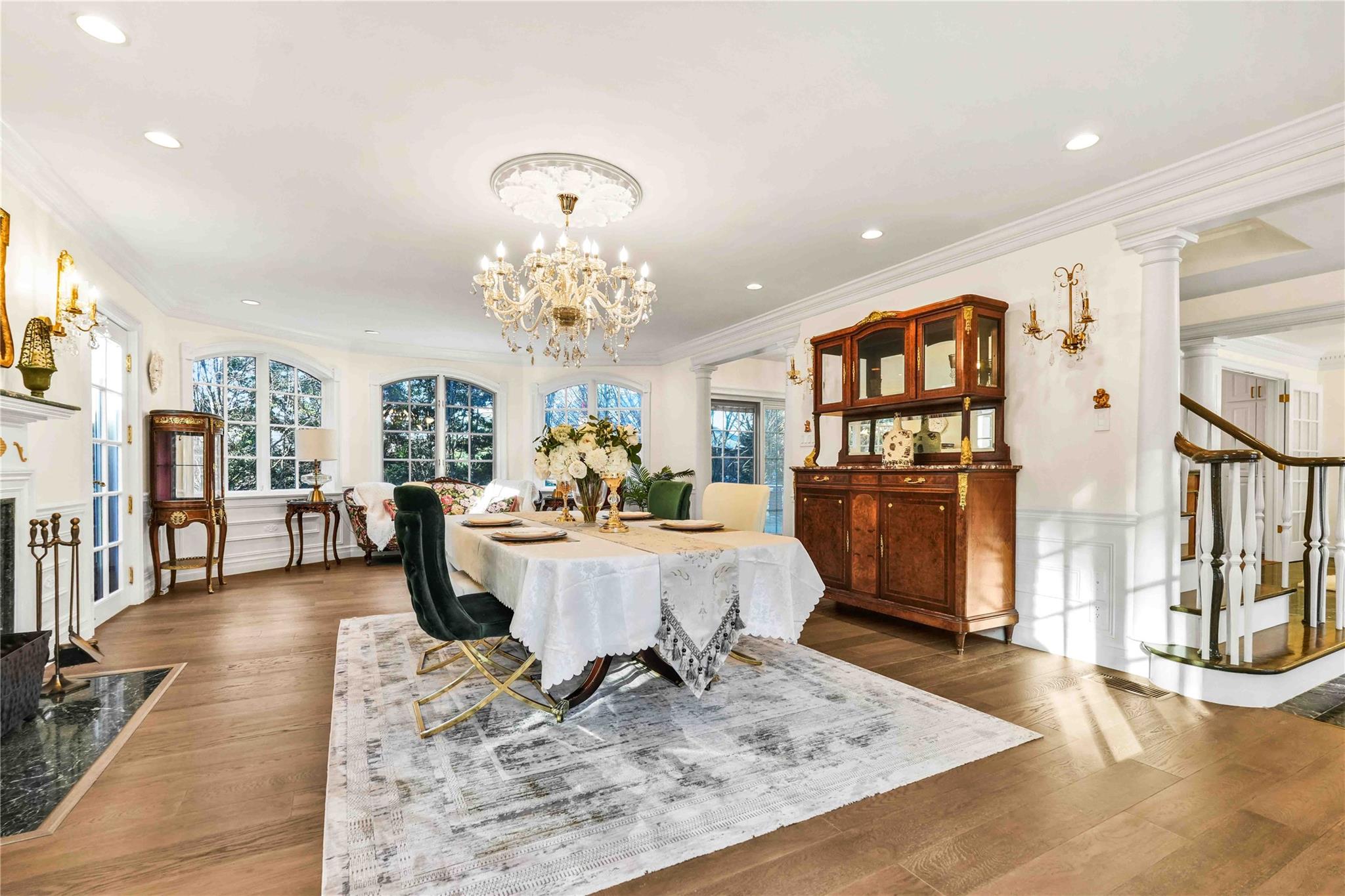 Dining area with dark hardwood / wood-style floors, a notable chandelier, decorative columns, crown molding, and a fireplace