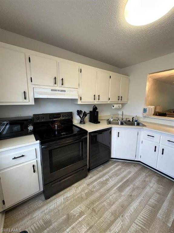 a kitchen with granite countertop a stove a sink dishwasher and white cabinets with wooden floor