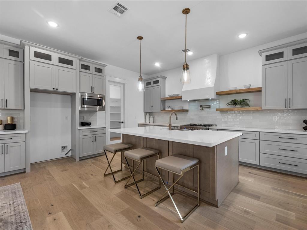 a kitchen with kitchen island granite countertop a sink cabinets and wooden floor