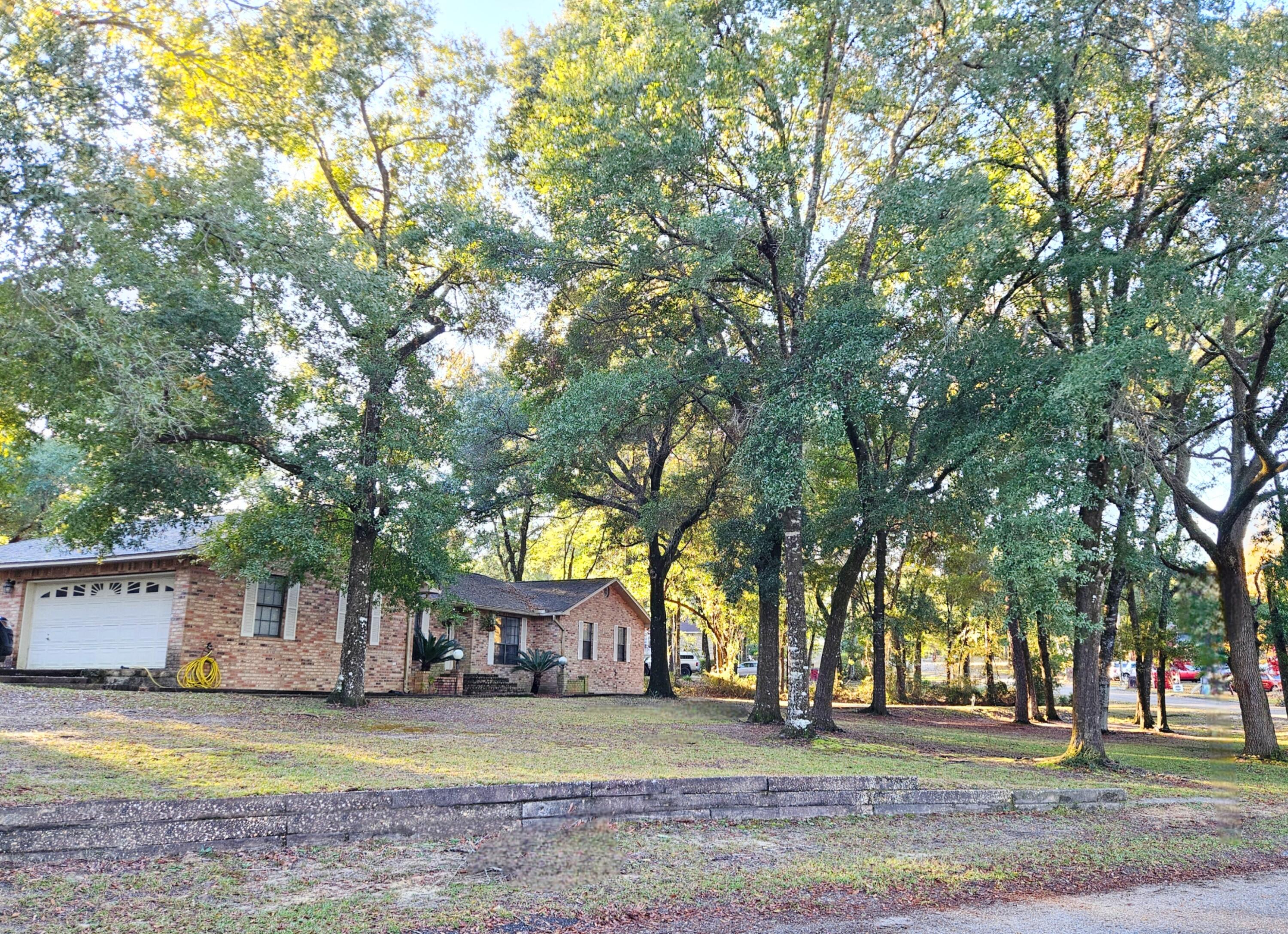 a view of a house with a yard and large trees