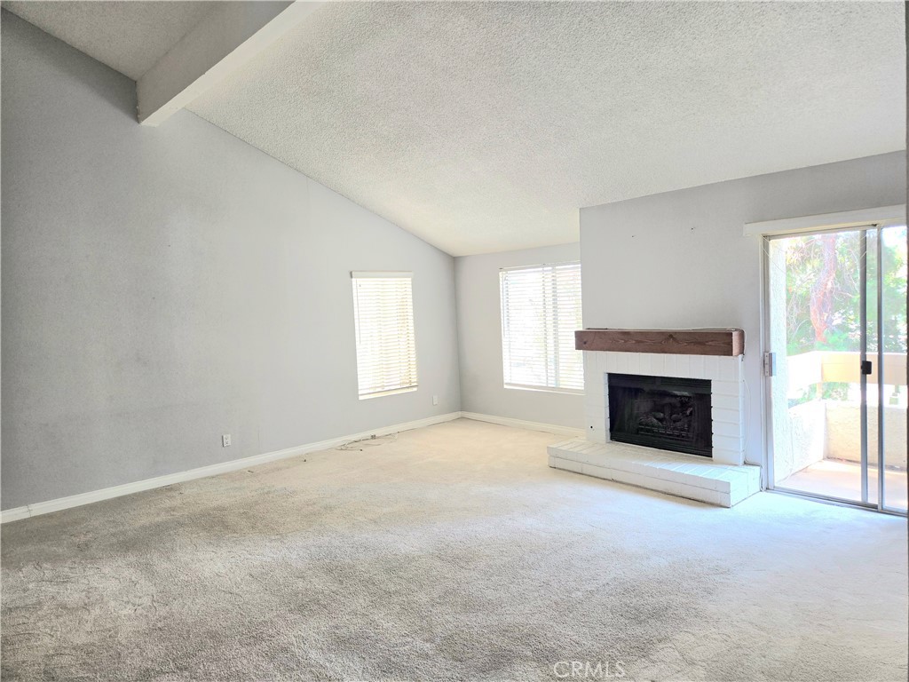 a view of an empty room with a window and fireplace