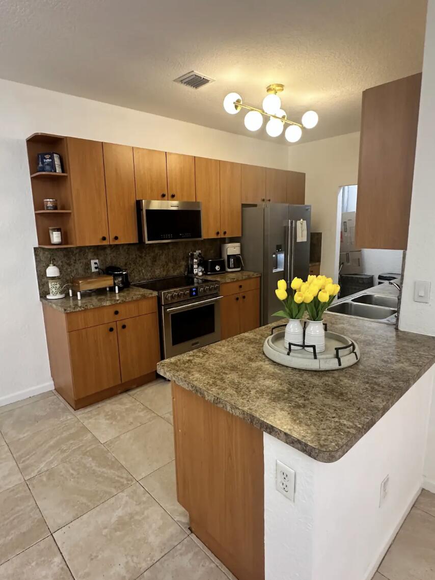 a kitchen with kitchen island granite countertop a sink cabinets and stainless steel appliances