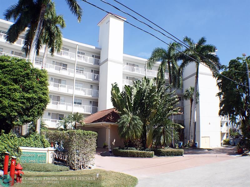 a view of a tall building with a yard and potted plants