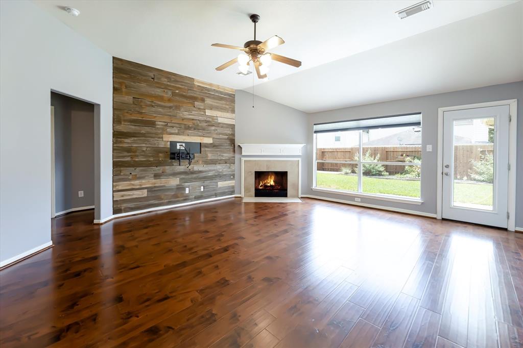 an empty room with fireplace wooden floor and windows