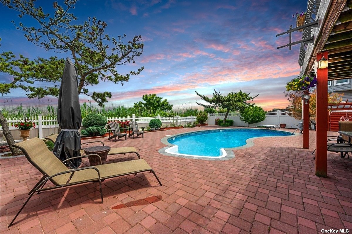 a view of swimming pool with seating space and trees