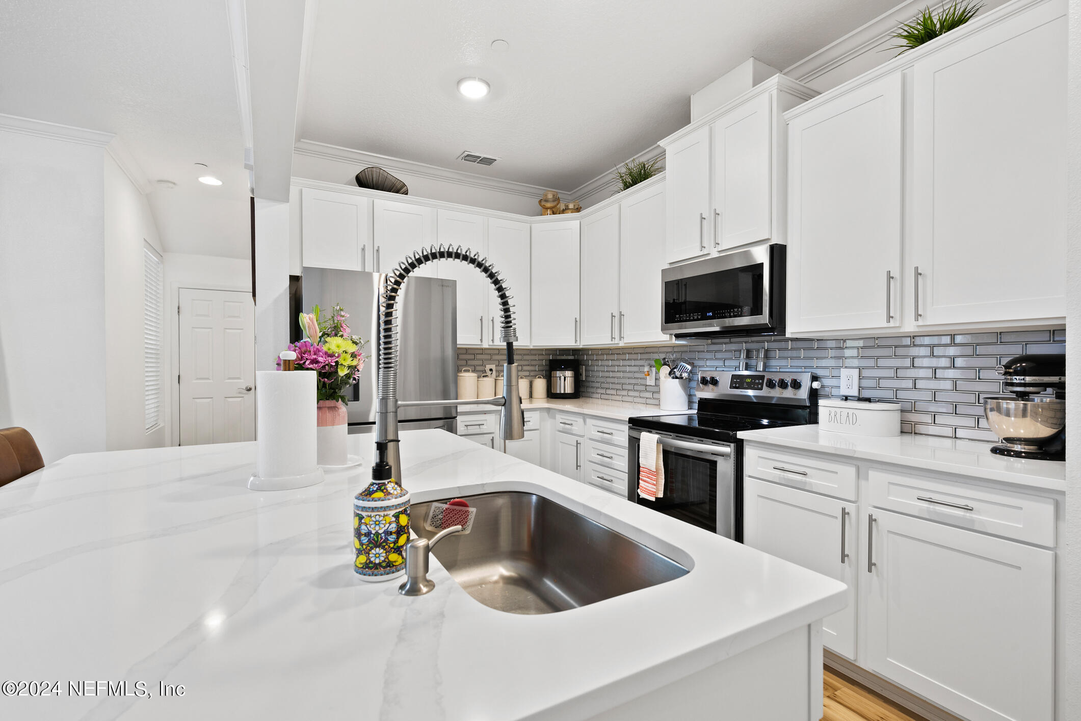 a kitchen with kitchen island a sink white cabinets and appliances