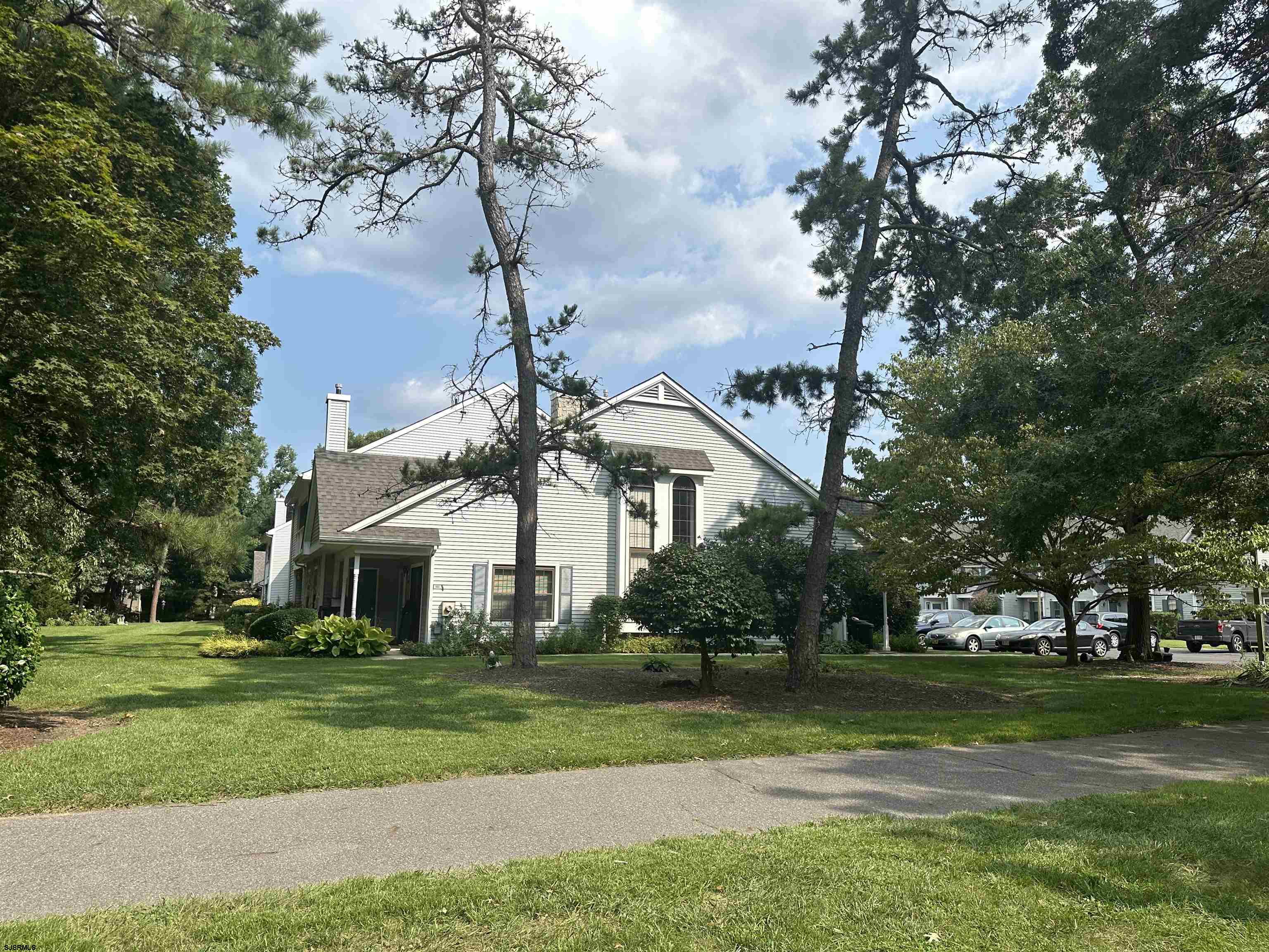 a view of a white house next to a yard with big trees