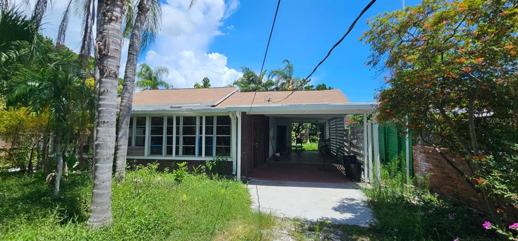 a view of a house with potted plants and a large tree