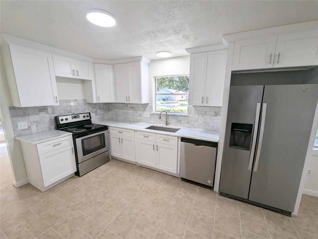 a kitchen with white cabinets stainless steel appliances and window