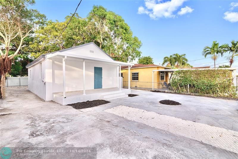 a view of backyard of house and car parked on road